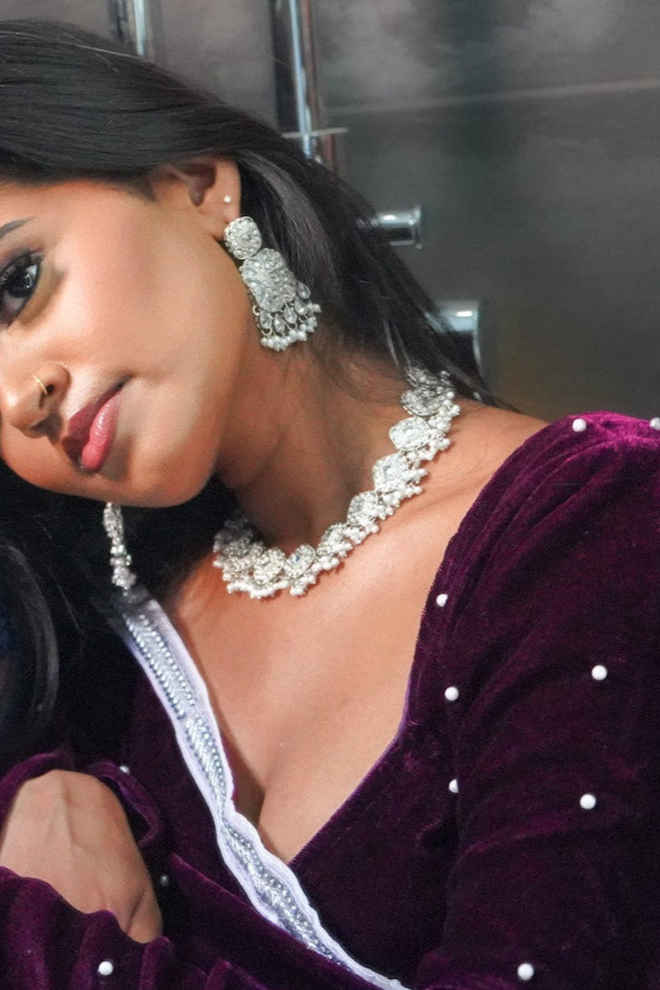 A women in traditional attire with jewelry, sitting close together.