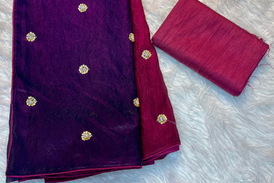 Purple fabric with gold embellishments and a matching red fabric on a white textured background